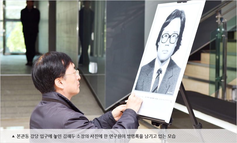 본관동 강당 입구에 놓인 김해두 소장의 사진에 한 연구원이 방명록을 남기고 있는 모습